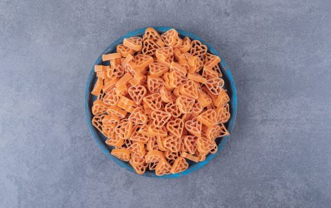 Pile of heart-shaped pasta on blue plate. High quality photo